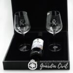 ESTUCHE  CON BOTELLA  VINO Y DOS COPAS. EN NEGRO  CON HAZ DE LICTORES  EN DORADO. (35 X 35 X 10 CM)